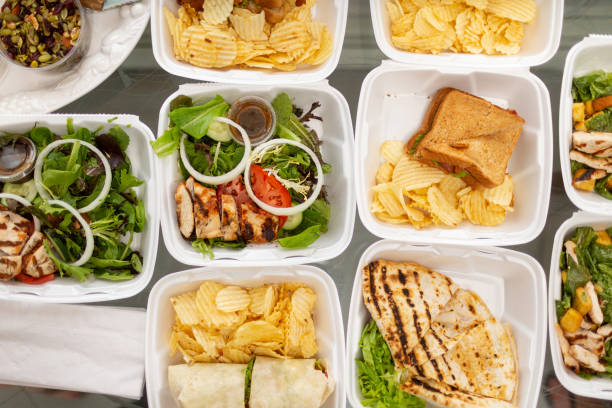 takeout food and containers full of sandwiches, salads and potatoe chips - junk food stock pictures, royalty-free photos & images