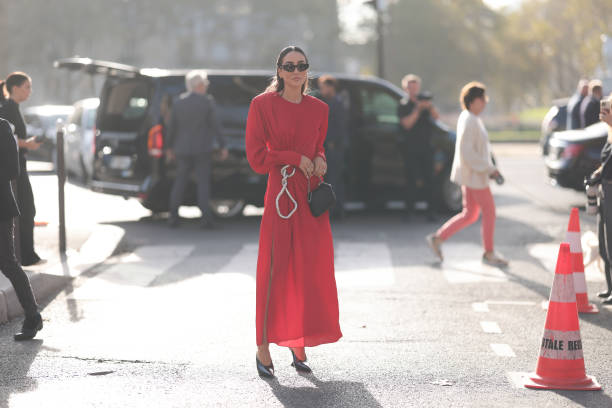 Tamara Kalinic is seen wearing long red dress, shoulder pads with side ruffles, silver chain and black leather handbag during the Stella McCartney...