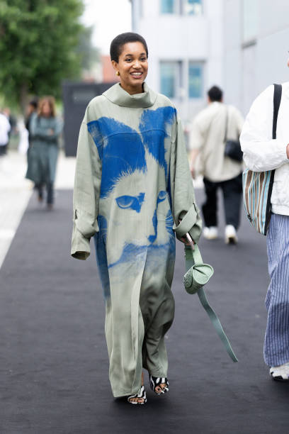 Tamu McPherson is seen wearing gold hoop earrings, a light olive green leather bag and a turtle neck light olive green oversized tracksuit with an...