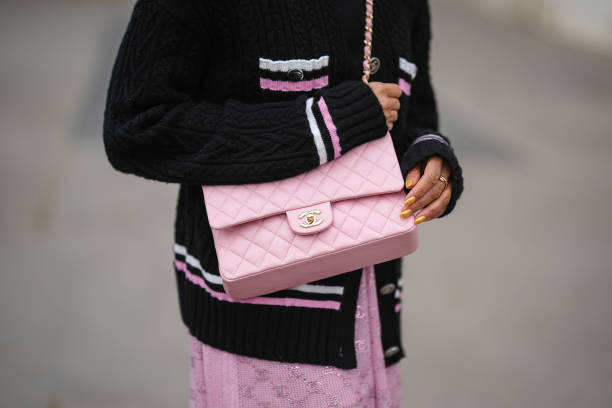 Tamu McPherson wears a black with white and pink embroidered white and pink striped borders pattern buttoned jacket from Chanel, a pale pink shiny...