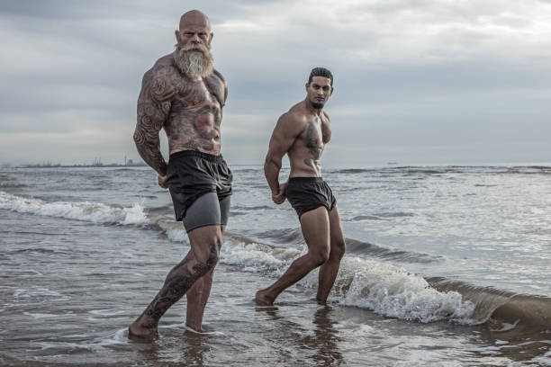 tattooed senior man coaching young man during workout - hairstyle stock pictures, royalty-free photos & images