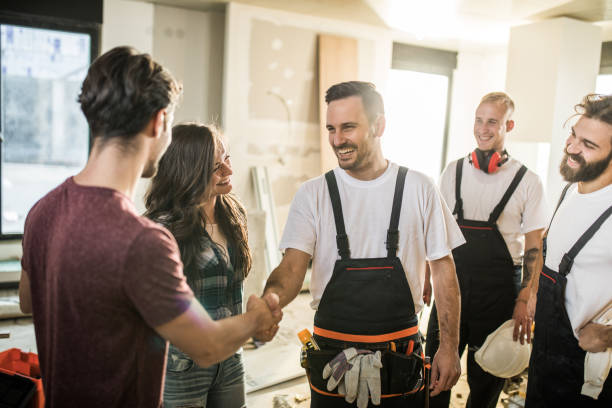 team of happy manual workers welcoming a couple to their apartment. - home decoration stock pictures, royalty-free photos & images