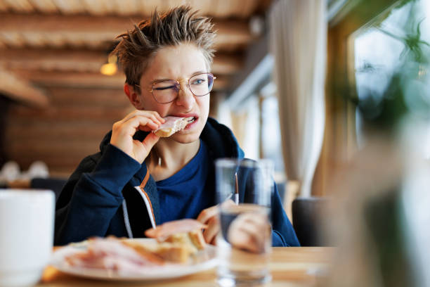 teenage boy eating a very tough sandwich - junk food stock pictures, royalty-free photos & images