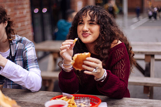 teenage girl eating fast food at street restaurant - junk food stock pictures, royalty-free photos & images