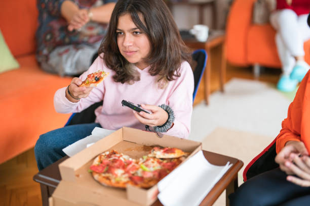 teenager girls playing video games and having fast food - junk food stock pictures, royalty-free photos & images