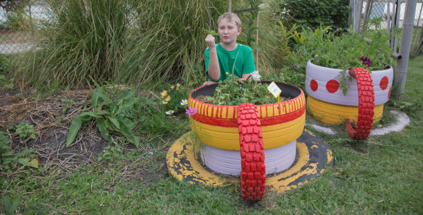 tending to flowers in recycled car tyres - garden decoration stock pictures, royalty-free photos & images