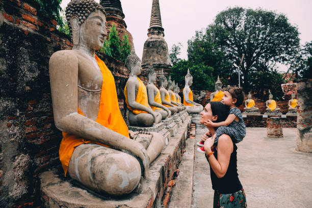 thailand, bangkok, ayutthaya, buddha statues in a row in wat yai chai mongkhon, mother and daughter in front of a buddha statue - travel stock pictures, royalty-free photos & images