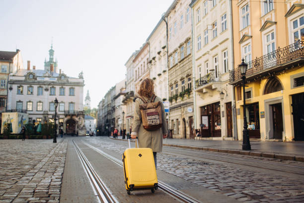 the beautiful cheerful woman with a suitcase walking on an ancient european street in the autumn - travel stock pictures, royalty-free photos & images