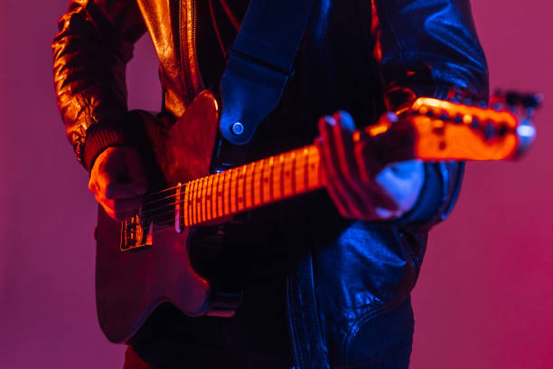 the guitar is close -up in the light of neon. unrecognizable man guitarist plays music on a musical instrument - concert stock pictures, royalty-free photos & images