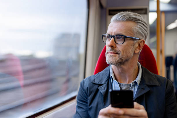 thoughtful man using his phone while riding on a train - travel stock pictures, royalty-free photos & images