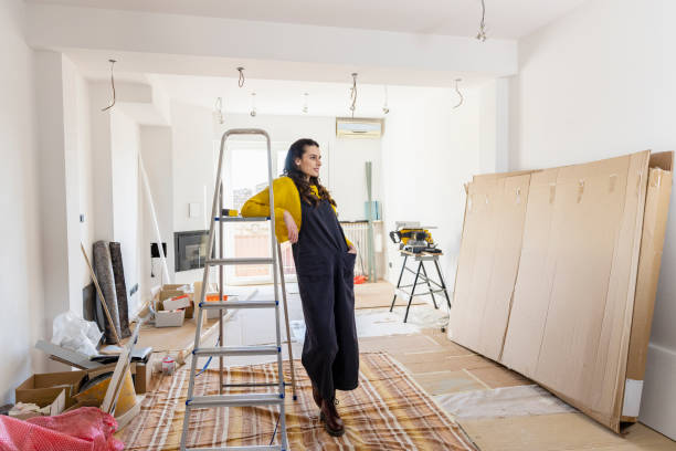 thoughtful woman leaning on ladder in new living room - home decoration stockfoto's en -beelden