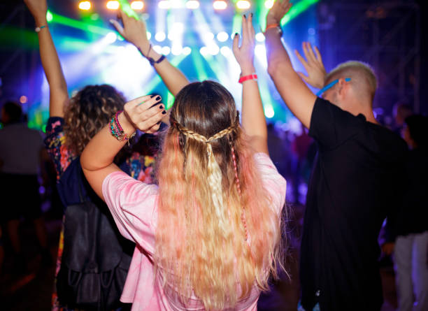 three friends cheering at outdoor music festival facing stage - concert stock pictures, royalty-free photos & images