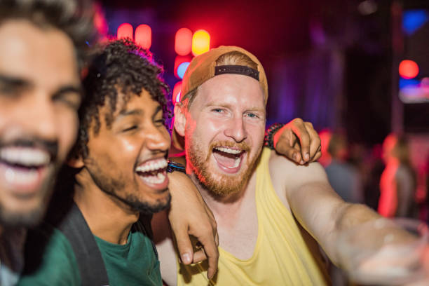 three happy young men partying at music festival at night. - concert stock pictures, royalty-free photos & images