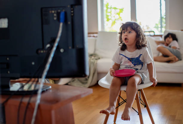 three year old boy eating in front of a television and surprised from what he see - junk food stock pictures, royalty-free photos & images