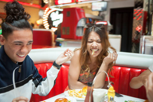 three young friends sitting in diner, laughing - junk food stock pictures, royalty-free photos & images