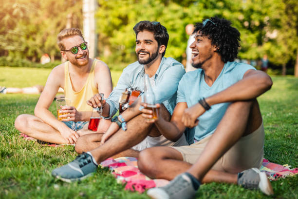three young men resting and drinking on a music festival. - concert stock pictures, royalty-free photos & images