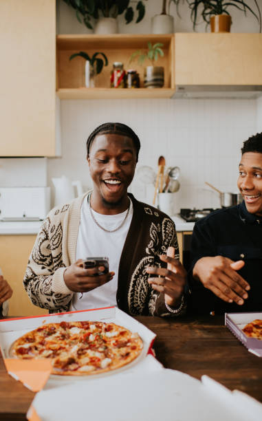 three young people open a box to reveal a full pizza - junk food stock pictures, royalty-free photos & images
