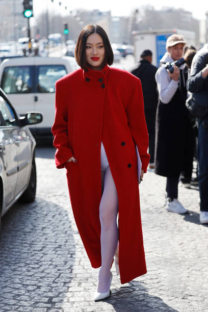 Tiffany Hsu wears red long coat, white tights, white heels, outside Givenchy, during the Womenswear Fall/Winter 2025/2026 as part of Paris Fashion...