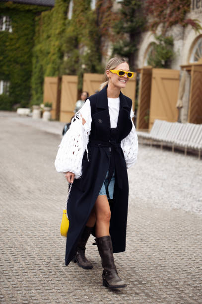 Tin Vcb wears a navy sleeveless coat, denim shorts and a white laced top outside Munthe during the Copenhagen Fashion Week Spring/Summer 2024 on...