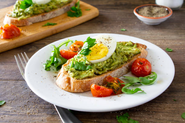 toast d’avocat avec des oeufs et des tomates rôties - food photos et images de collection