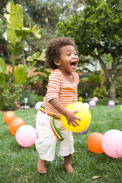 toddler boy (21-24 months) playing with balloons in yard - garden decoration stock pictures, royalty-free photos & images