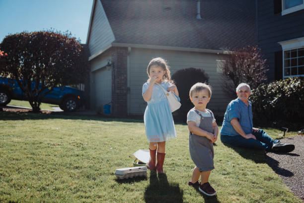 toddler siblings begin an easter egg hunt outside their home - garden decoration stock pictures, royalty-free photos & images