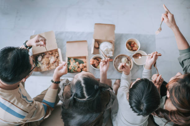 top view asian chinese young family enjoying take out food in front of tv in living room during weekend - junk food stock pictures, royalty-free photos & images