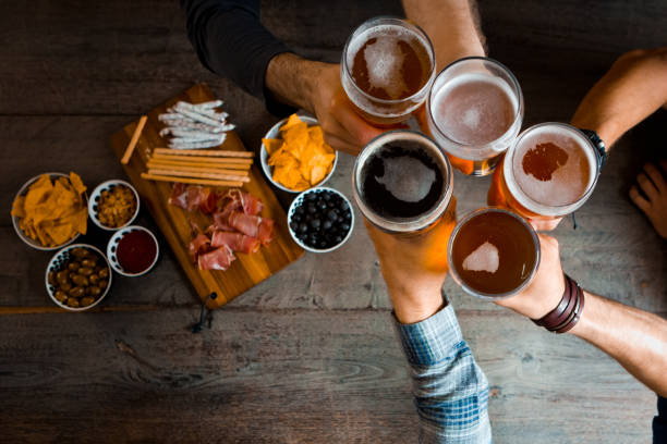 top view of friends toasting with beer glasses in the pub - food stock pictures, royalty-free photos & images