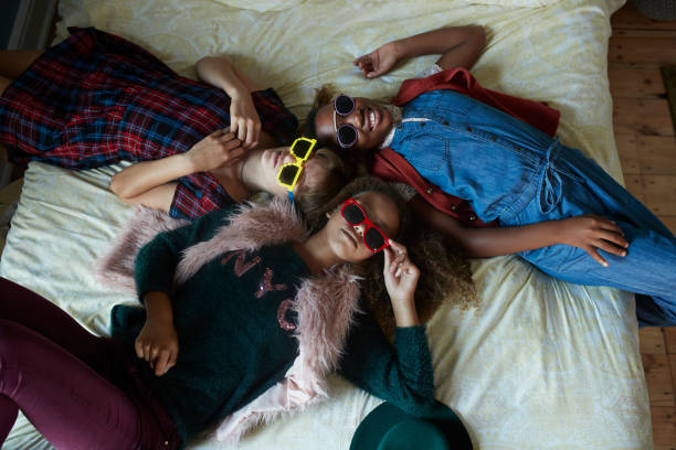 top view of girlfriends relaxing in bed and wearing weird glasses - fashion stock pictures, royalty-free photos & images