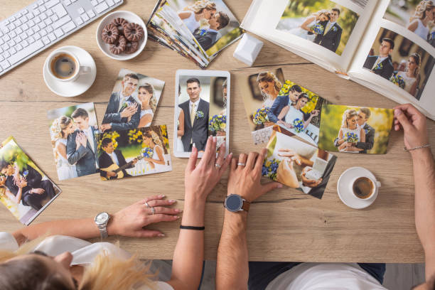 top view of wedding pictures collection on a table, viewed by a couple having coffee and biscuits. - home decoration stock pictures, royalty-free photos & images