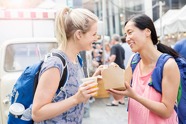 tourists sharing lunch at food market - junk food stock pictures, royalty-free photos & images