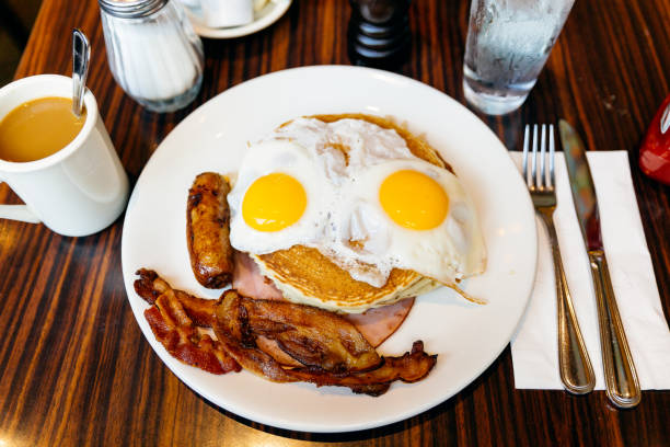 traditional american breakfast with pancakes, fried eggs, bacon, sausage and ham served in a diner - junk food stock pictures, royalty-free photos & images