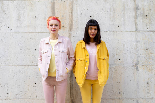 two alternative friends having fun, wearing yellow and pink jeans clothes - fashion stock pictures, royalty-free photos & images