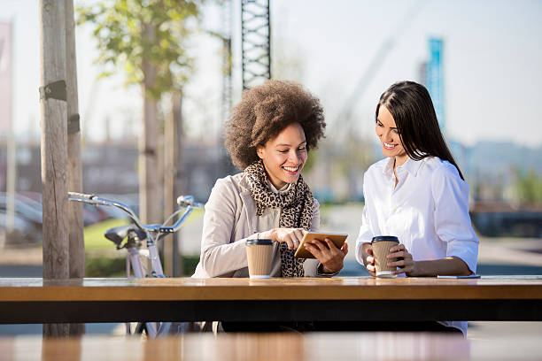 two beautiful females drinking coffee to go - junk food stock pictures, royalty-free photos & images