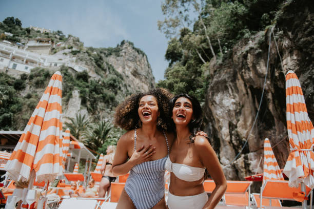two beautiful young woman look thrilled to be standing on a sunny beach in paradise - travel stock pictures, royalty-free photos & images