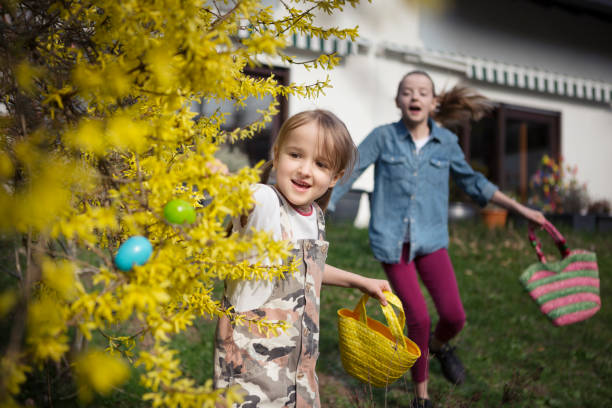 two children running in a back yard searching for easter eggs - garden decoration stock pictures, royalty-free photos & images