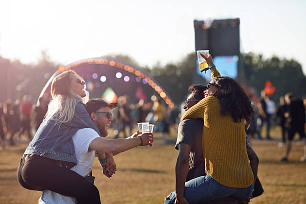 two couples piggybacking at big festival outside - concert stock pictures, royalty-free photos & images