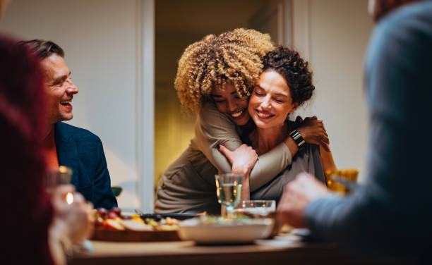 two friends hugging during a dinner celebration - food stock pictures, royalty-free photos & images