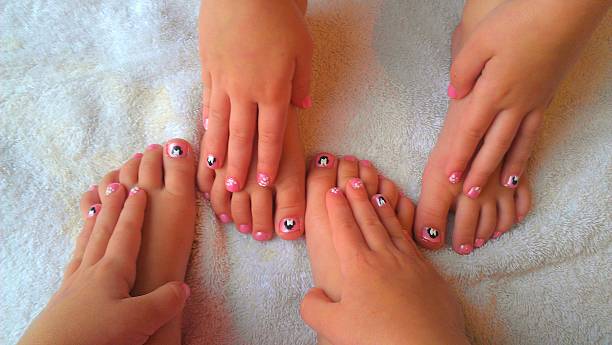 two girls with nail art on fingernails and toenails - nails art photos et images de collection