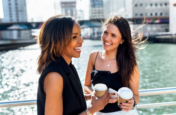 two happy women having a coffee break on a bridge in the city - junk food stock pictures, royalty-free photos & images