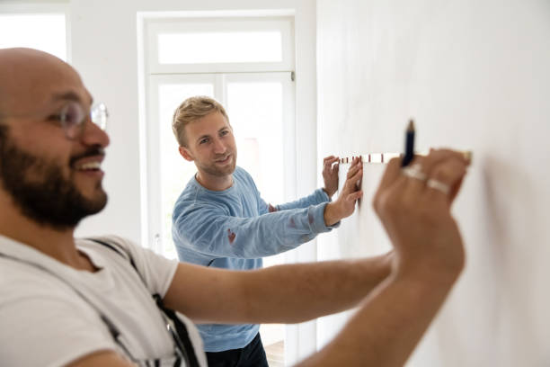 two male friends taking measurements using a measuring tape - home decoration stock pictures, royalty-free photos & images