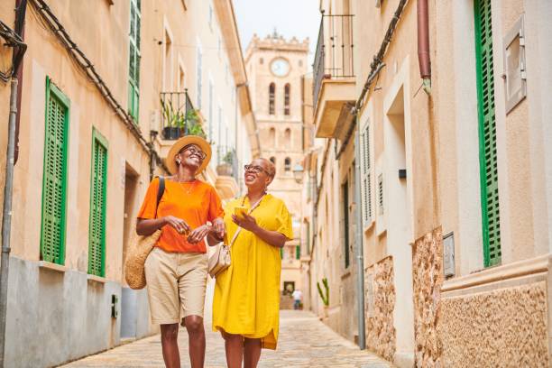 two mature women walking together exploring an old town in europe. - travel stock pictures, royalty-free photos & images