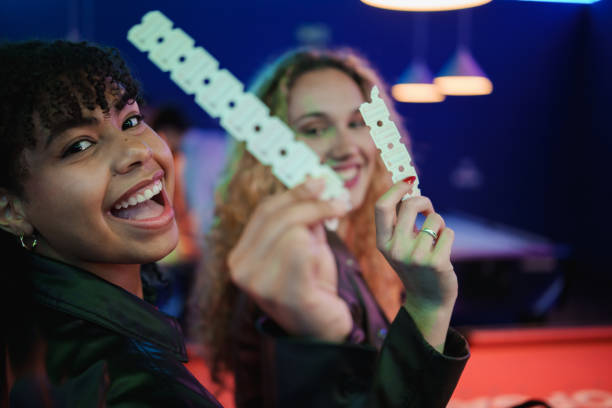 two young women holding tickets and smiling at an event - concert stock pictures, royalty-free photos & images