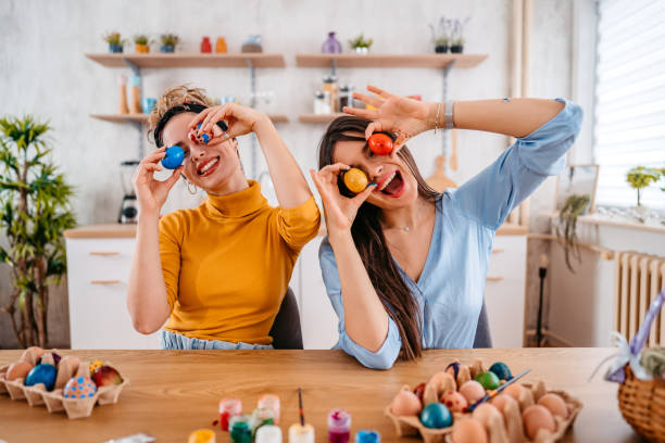 two young women holding up easter eggs - home decoration stock pictures, royalty-free photos & images