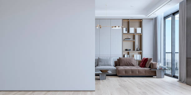 una gran pared blanca en blanco frente a una sala de estar contemporánea con un gran sofá, sillón y mesa de café frente a un armario empotrado con estanterías y decoración, y ventanas al otro lado - home decoration fotografía