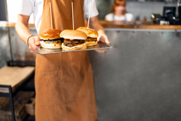 unrecognizable male teenager holding tray with burgers, at the fast food restaurant - junk food stock pictures, royalty-free photos & images