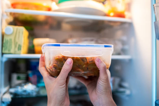 unrecognizable woman putting a tupper with food in the refrigerator - food stock-fotos und bilder