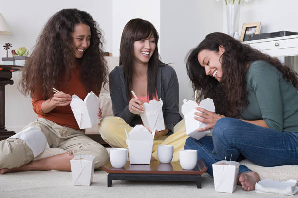 usa, california, los angeles, three female friends eating take out food at home - junk food stock pictures, royalty-free photos & images