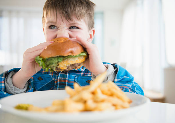 usa, new jersey, jersey city, portrait of boy (4-5) eating hamburger - junk food stock pictures, royalty-free photos & images