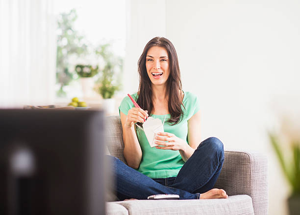 usa, new jersey, jersey city, portrait of woman watching tv and eating take out food - junk food stock pictures, royalty-free photos & images